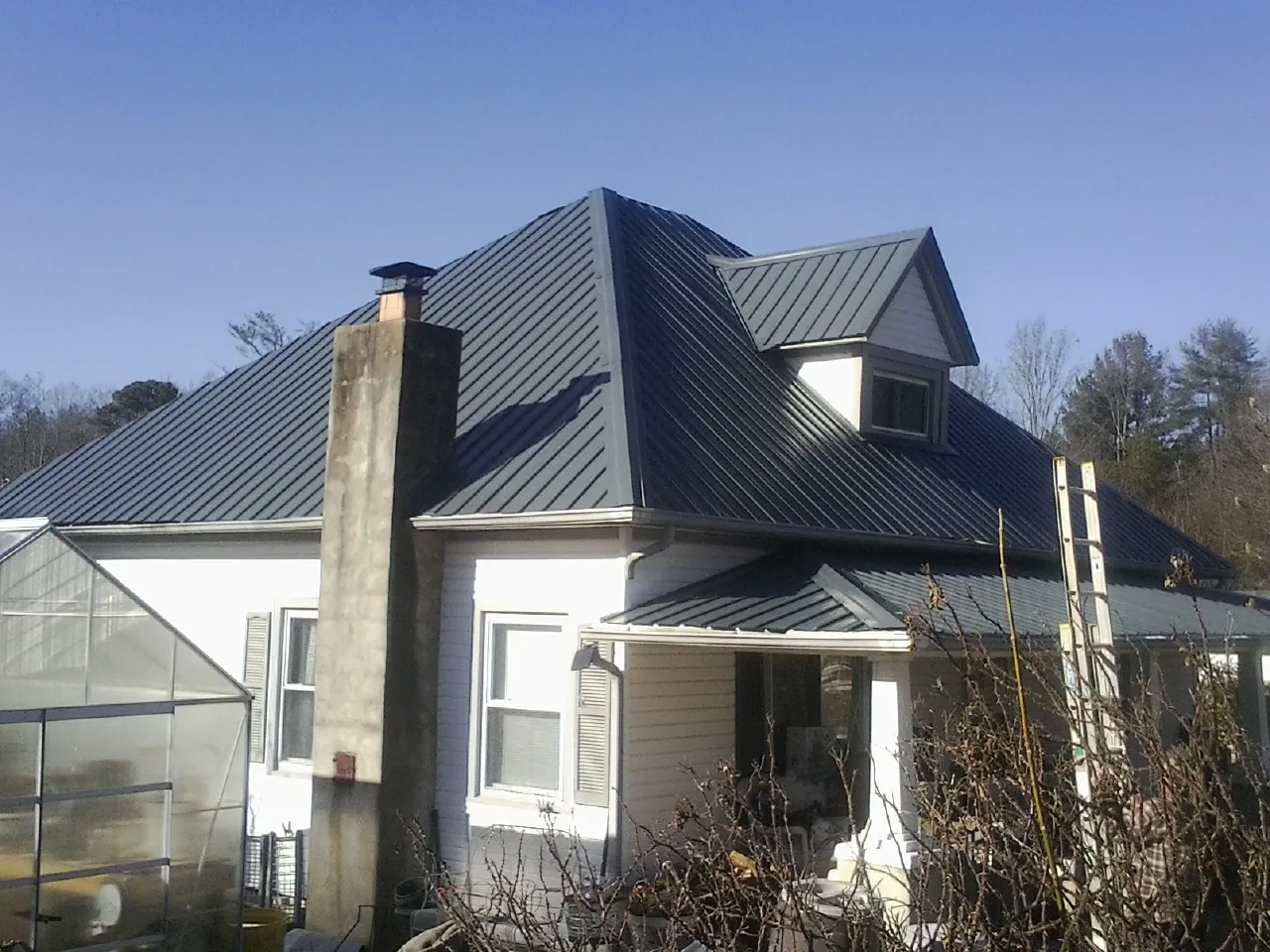 Dark blue standing seam metal roof on a white farmhouse with dormer — Slate & Tile Roof Repair by Roofing Brothers in Ouray