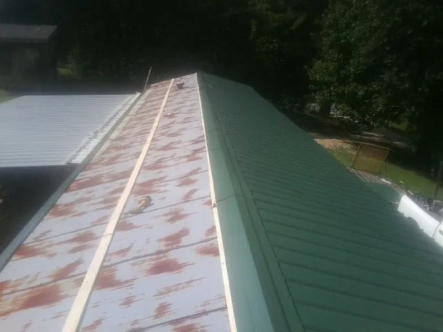 Old rusted panels beside newly installed green metal roofing — Wind Damage Roof Repair by Roofing Brothers in Ouray