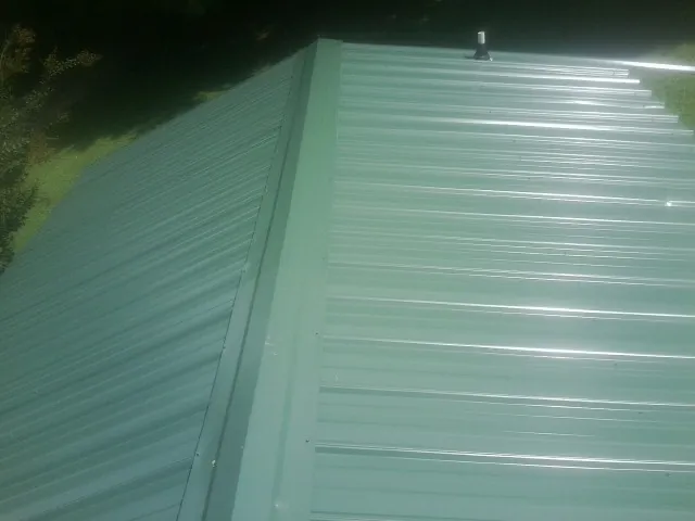 New green metal panels meeting at the ridge of a roof — Flat Roof Repair work by our crew in Ouray