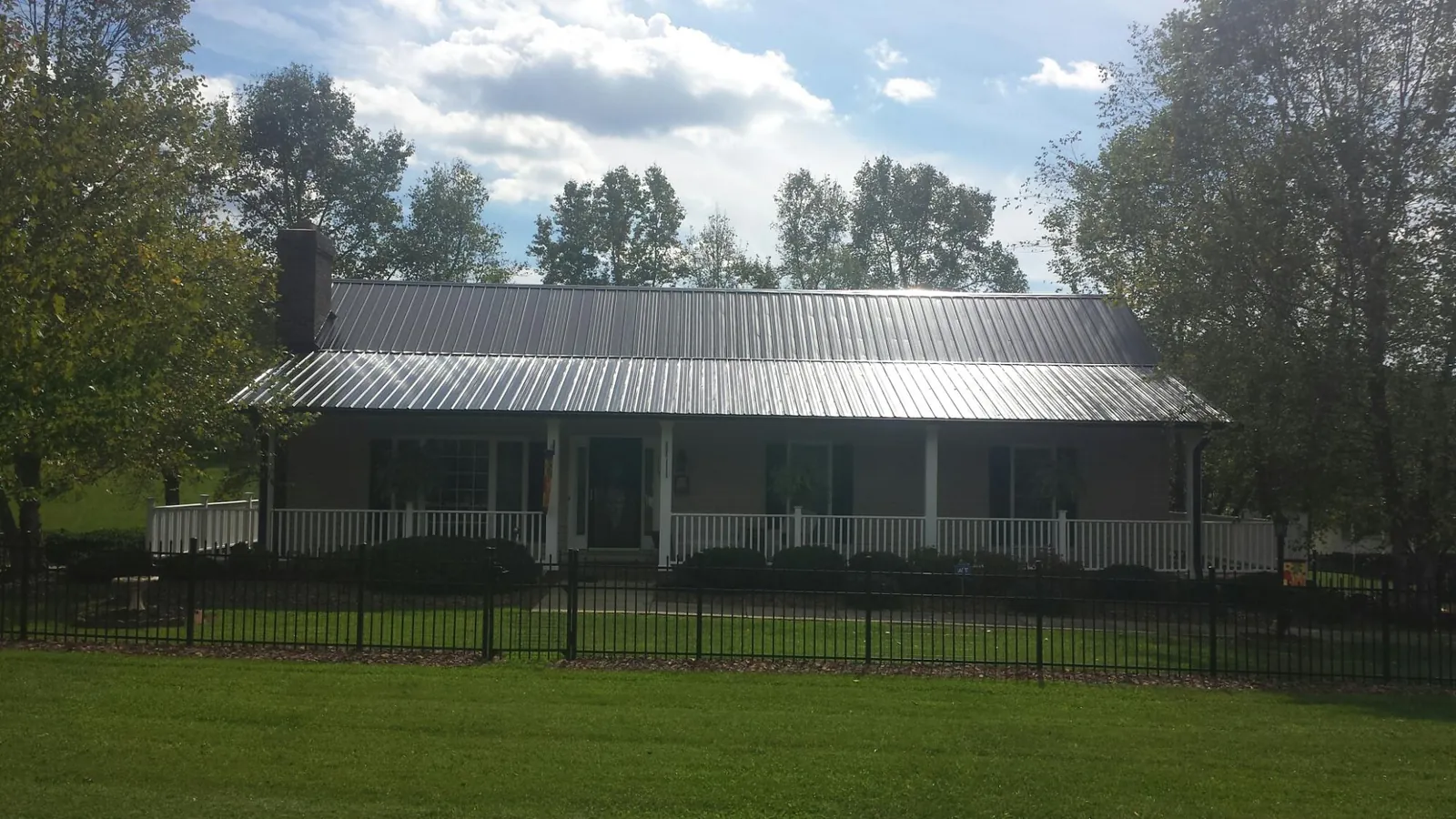 Gray metal roof on a brick ranch with a full width front porch — Gutter Guard Installation work by our crew in Ouray