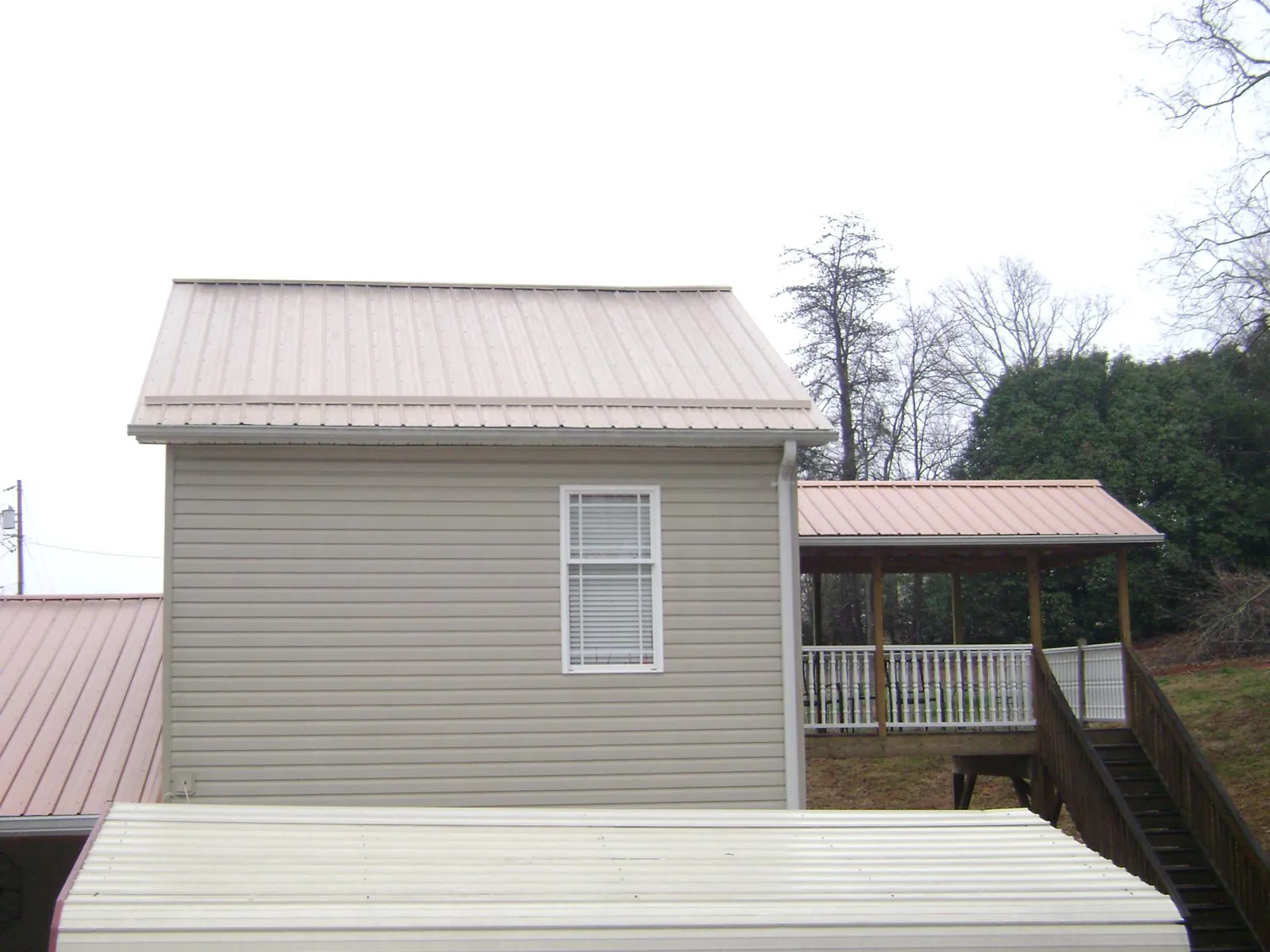 Tan metal roofs on a two story addition and attached porch, from a Roof Replacement job in Ouray