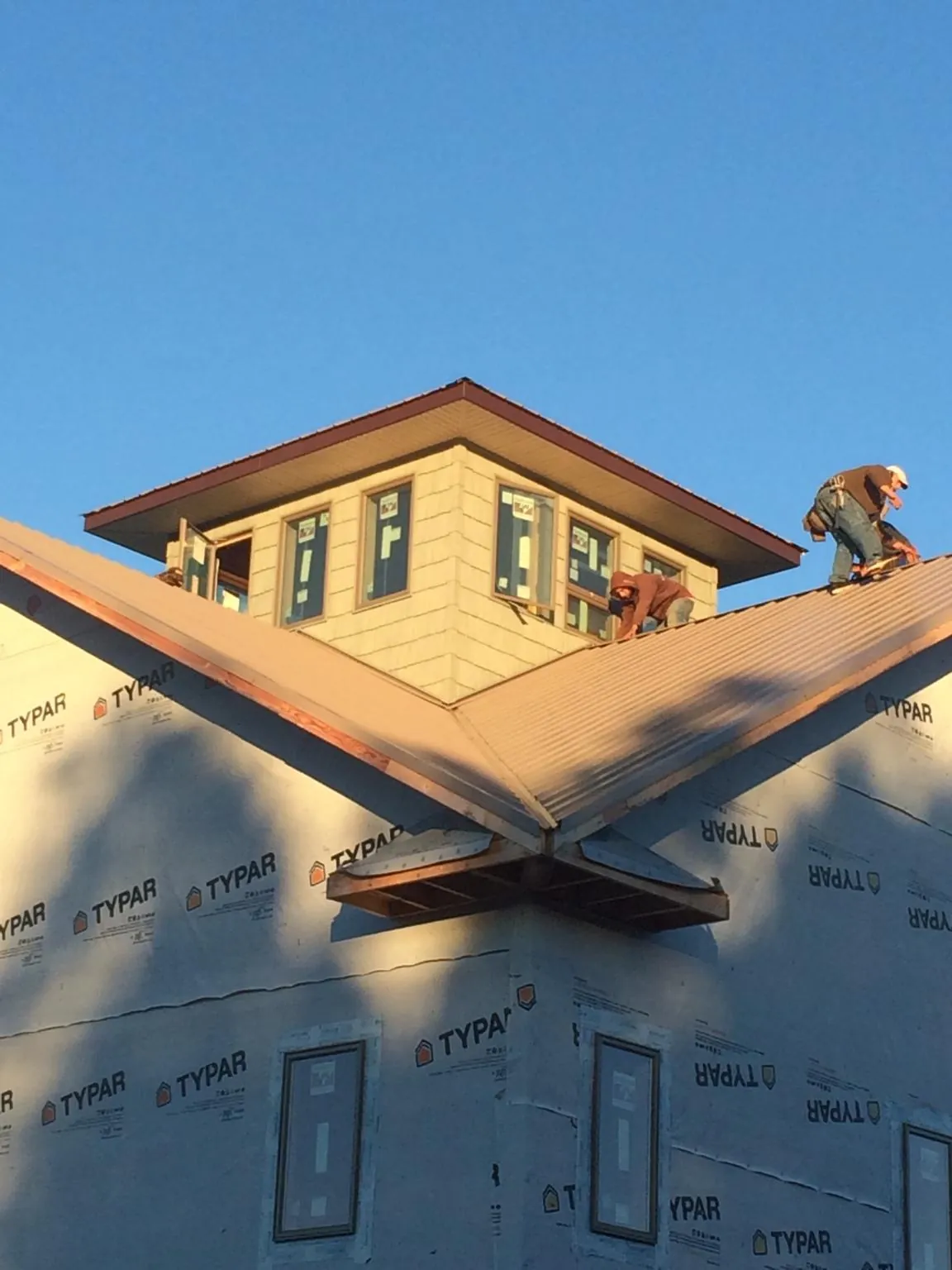Roofers working around a rooftop cupola on a new metal roof at sunset — Roof Waterproofing in Ouray by Roofing Brothers